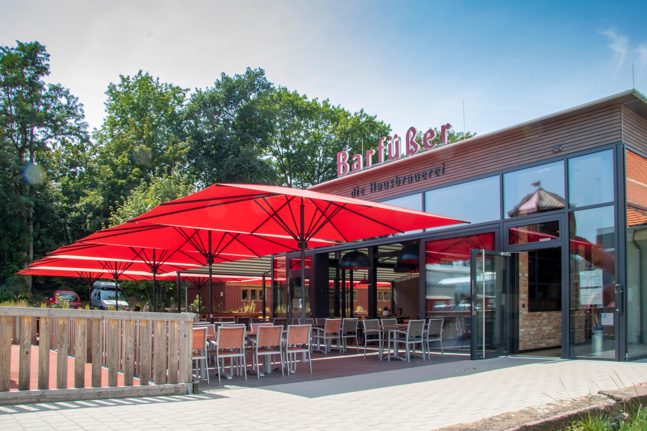 Restaurant von Außen mit vier roten Sonnenschirmen auf der Terrasse